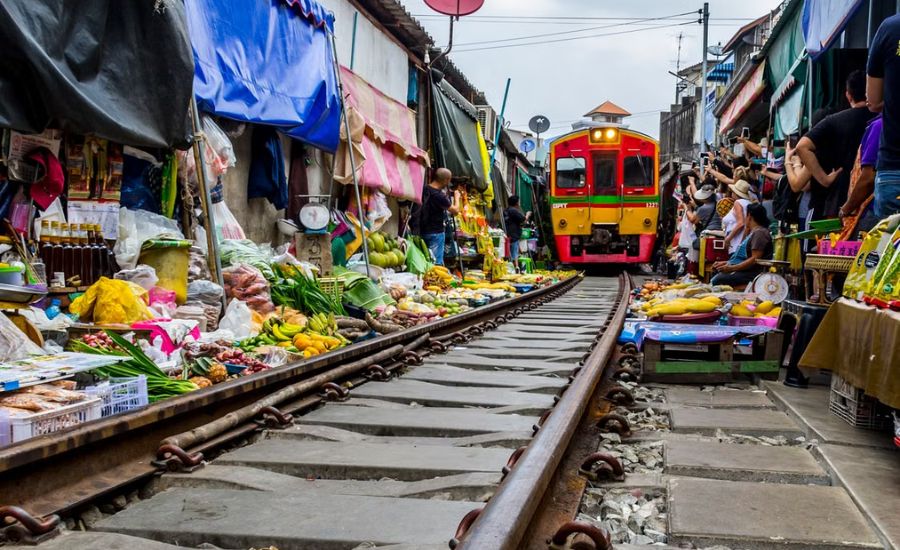 A train passing directly through the bustling stalls of Mae Klong Railway Market