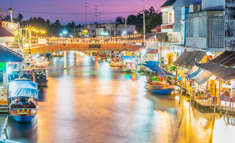 Amphawa Floating Market illuminated with warm lights as evening settles along the canal