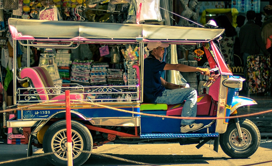 Pink tuk-tuk driving on a street in Chiang Saen