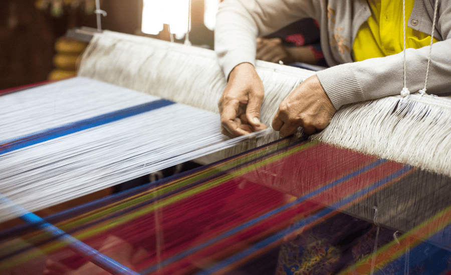 Thai artists weaving silk from a handweaving machine