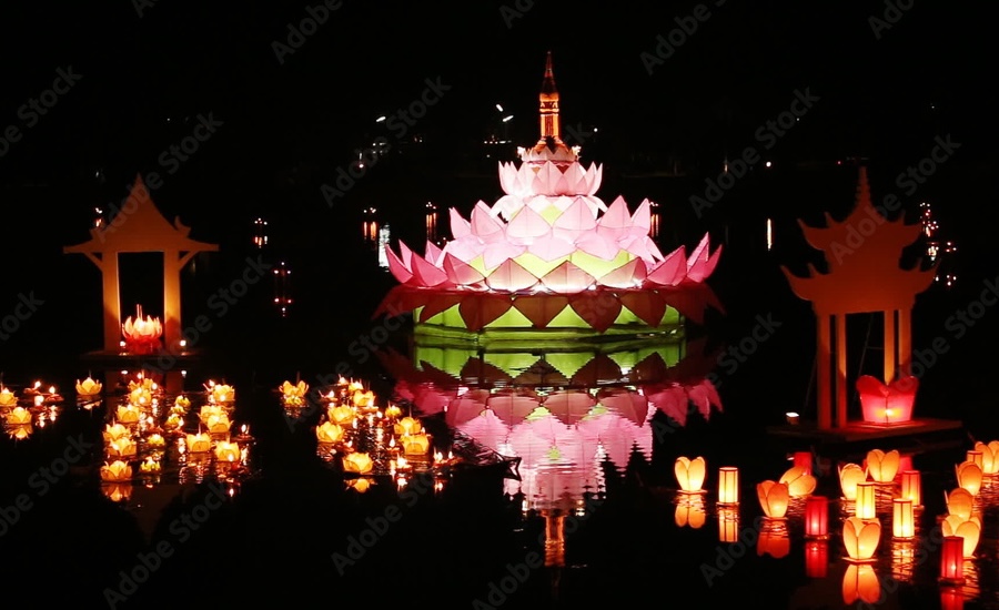 Large glowing pink lotus float surrounded by candles.